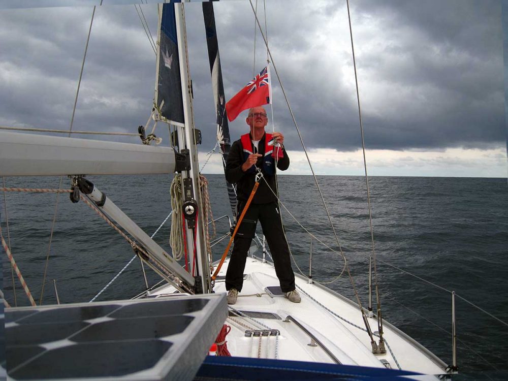 Cees van Dijk hijst de Red Ensign, de Britse gastenvlag, als hij met de NOMAS naar Engeland zeilt.